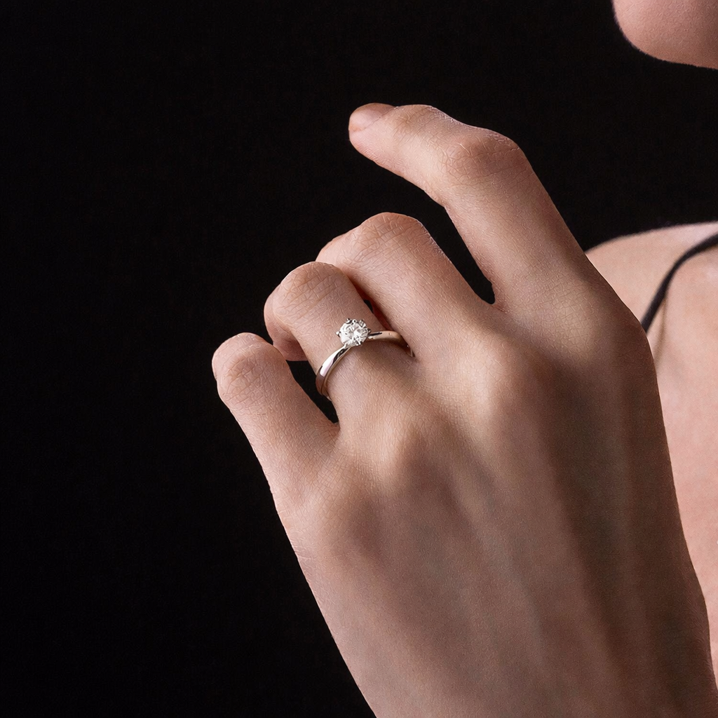 Hand wearing a diamond ring on a black background
