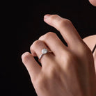 Hand wearing a diamond ring against a black background