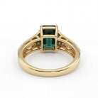 This MYZA Certified 1.5 Carats Emerald Cut Zambian Green Women's Ring  features a vivid lab-grown Zambian emerald in a 14K hallmarked gold setting, offering a sleek, sophisticated balance of classic step-cut elegance and brilliant diamond accents.