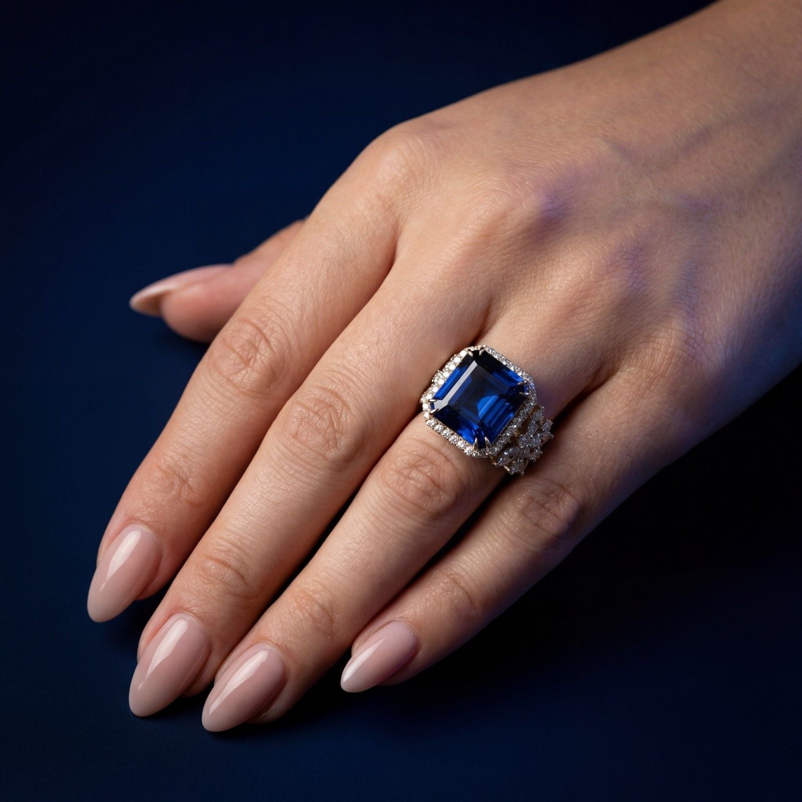 This MYZA Certified 10.12-carat Asscher-cut ring features a magnificent lab-grown Sapphire blue gemstone centerpiece encircled by a&nbsp;brilliant diamond halo and flanked by exquisite marquise diamond floral clusters, all set in premium 14K hallmarked gold
